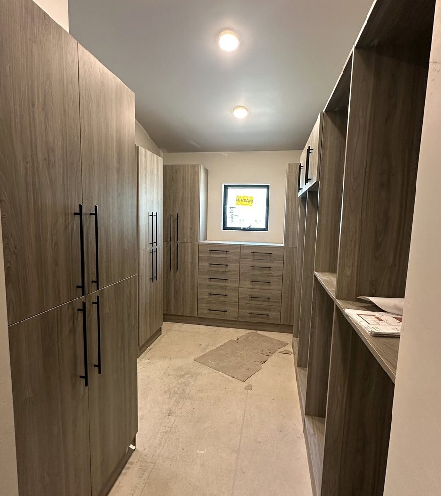 Walk-in closet with tall cabinets and drawers in a new home